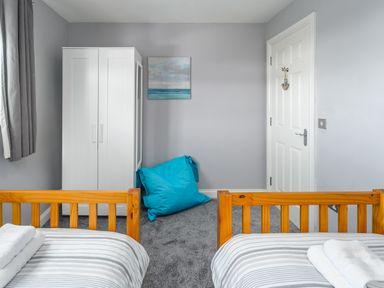 A bedroom with two wooden beds a white wardrobe and a blue bean bag at 39 Longbeach Drive in Beadnell