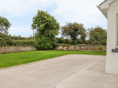 A driveway and grass lawn bordered by a low wall with trees at Dirreen House in Athea near Listowel County Kerry