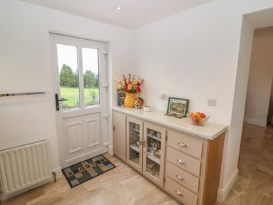 A hallway with a white door a welcome mat and a cabinet with drawers and glass doors holding dishes at Dirreen House in Athea near Listowel County Kerry