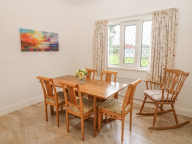 A dining room with wooden table and chairs a rocking chair and a window with floral curtains at Dirreen House Athea near Listowel County Kerry