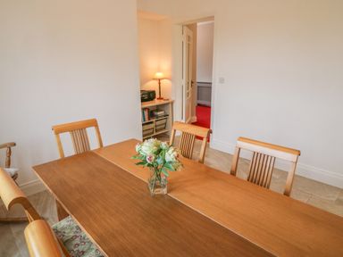 A dining room with a wooden table and chairs and a vase of flowers on the table at Dirreen House in Athea near Listowel County Kerry