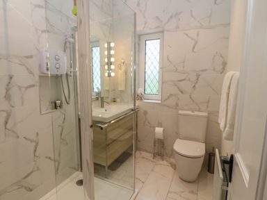 A bathroom with a shower, toilet, sink, and a small window at Dirreen House in Athea near Listowel County Kerry