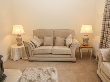 A beige sofa with cushions between two table lamps on side tables in a living room at Dirreen House Athea near Listowel County Kerry