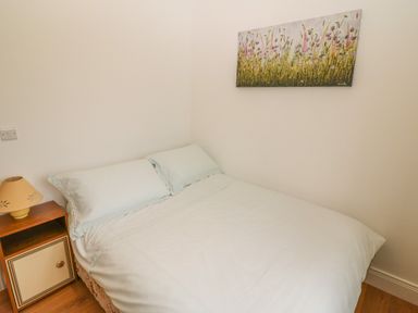 A bedroom with a bed side table and a lamp and a floral painting on the wall at Dirreen House Athea near Listowel County Kerry