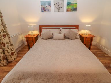 A bedroom with a double bed two bedside tables with lamps and three paintings on the wall at Dirreen House Athea near Listowel County Kerry