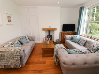 A living room with two sofas a wooden coffee table and a television at Copybush Cottage in Lawrenny