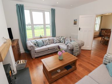 A living room with two armchairs wooden coffee table and teal curtains at Copybush Cottage in Lawrenny
