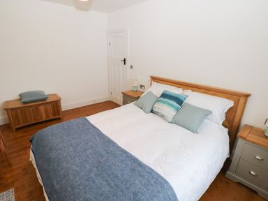 A bedroom with a wooden bed white and blue bedding bedside tables and a wooden chest at Copybush Cottage in Lawrenny