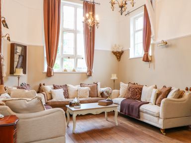 A living room with sofas pillows and a coffee table in front of windows with curtains at The Old School in Downham Market