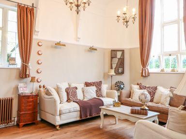 A sitting room with sofas cushions coffee table and windows with curtains at The Old School in Downham Market