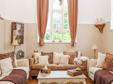 A sitting room with sofas cushions a coffee table a globe and a window with curtains at The Old School in Downham Market