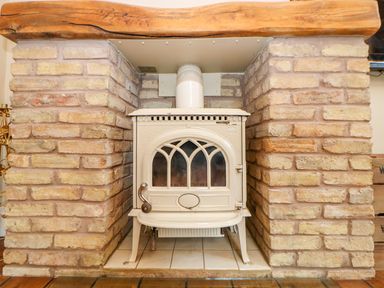 A cream wood burning stove set into a brick fireplace at The Old School in Downham Market