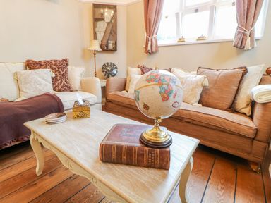 A living room with two sofas cushions a globe on a book and a table at The Old School in Downham Market