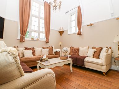 A sitting room with sofas cushions and a coffee table on wooden floor at The Old School in Downham Market