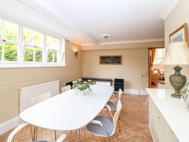A dining room with a white table and chairs a lamp and a plant on the table at The Old School in Downham Market