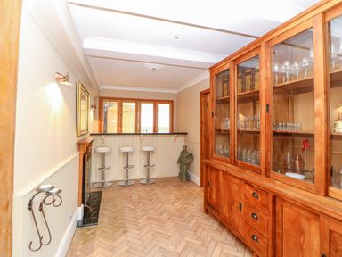 A dining room with a wooden cabinet glassware and three bar stools at The Old School in Downham Market