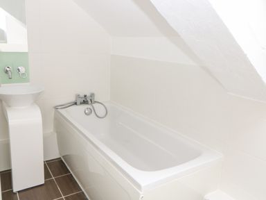 A bathroom with a bathtub and a sink under a slanted ceiling at The Old School in Downham Market