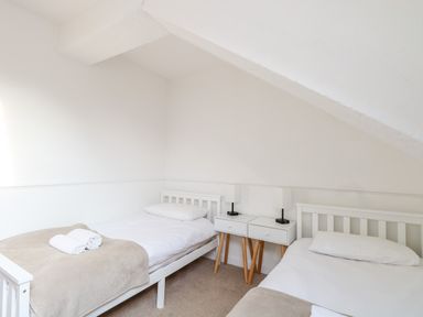A bedroom with two single beds and a shared bedside table with lamps at The Old School in Downham Market