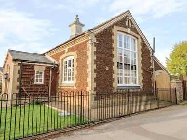 Exterior of a building with large windows black metal fence and grass at The Old School in Downham Market