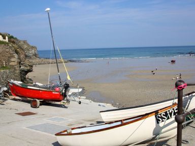 Boats on a concrete ramp leading to a beach with people and dogs near the ocean at Idlewild 2 Wheal Turnavore in St Agnes