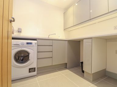 A utility room with a washing machine sink and grey cabinets at Idlewild 2 Wheal Turnavore in St Agnes