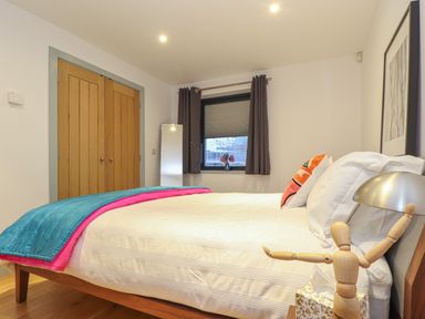 A bedroom with a wooden bed with white bedding and a blue and pink blanket at Idlewild 2 Wheal Turnavore in St Agnes