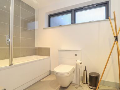 A bathroom with a bathtub and a toilet under a window at Idlewild 2 Wheal Turnavore in St Agnes