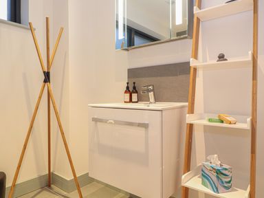 A bathroom corner with a white sink cabinet wooden towel rack and white shelving ladder at Idlewild 2 Wheal Turnavore in St Agnes