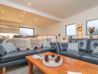 A living room with two black leather sofas and a wooden coffee table at Idlewild 2 Wheal Turnavore in St Agnes
