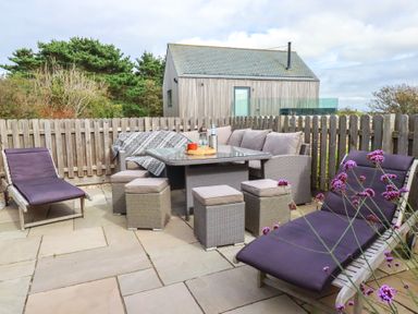 An outdoor seating area with a table and lounge chairs at Idlewild, 2 Wheal Turnavore St Agnes