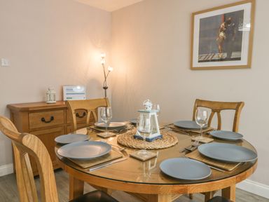 A dining room with a round wooden table set for six people and wooden chairs at 2 The Close in Robin Hood's Bay