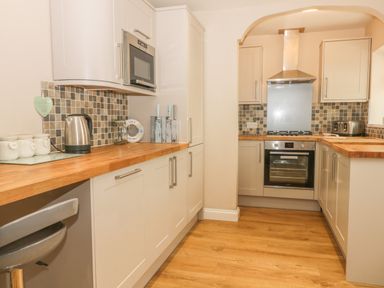 A kitchen with white cabinets wooden countertops a stainless steel oven and stove a microwave kettle and toaster at 2 The Close in Robin Hood'S Bay