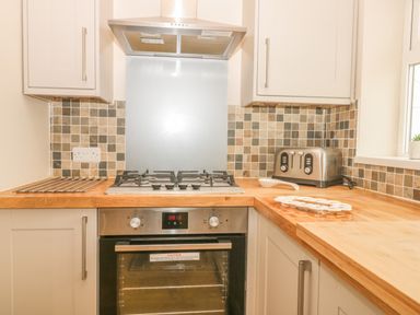 A kitchen with a gas stove oven stainless steel toaster and wooden countertops at 2 The Close in Robin Hood'S Bay