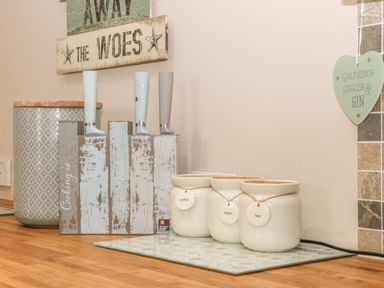 A kitchen countertop with three labeled ceramic jars for coffee sugar and tea next to a knife set with light blue and gray handles and a lidded container at 2 The Close in Robin Hood'S Bay