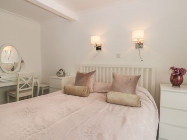 A bedroom with a double bed two bedside tables a dressing table with a chair and wall lamps at 2 The Close in Robin Hoods Bay