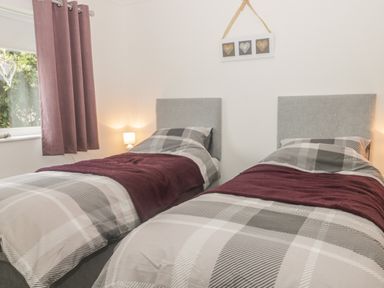 A bedroom with two single beds with checkered bedding and purple blankets at 2 The Close in Robin Hood's Bay