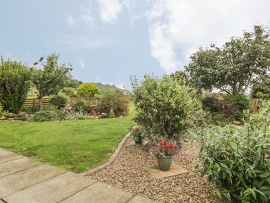 A garden with grass lawn gravel area flowers shrubs and trees at 2 The Close in Robin Hood'S Bay