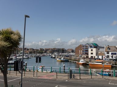 A harbor with boats docked along the water and buildings in the background at Sailor's Watch in Weymouth