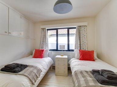 A bedroom with two single beds a nightstand and a window at Sailor's Watch in Weymouth