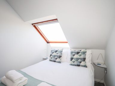 A small bedroom with a double bed under a slanted ceiling window at Isallt Cove in Trearddur Bay