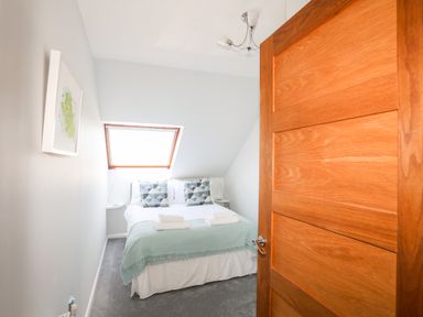 A bedroom with a bed two pillows and a window at Isallt Cove in Trearddur Bay