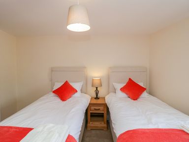 A bedroom with two single beds a wooden nightstand and a lamp at Golden Valley Barn in Oldbury-On-Severn