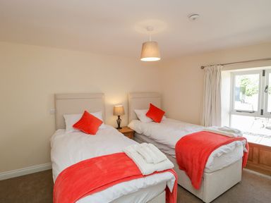 A bedroom with two single beds and a window at Golden Valley Barn in Oldbury-On-Severn
