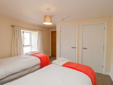 A bedroom with two single beds and a window with curtains at Golden Valley Barn in Oldbury-On-Severn
