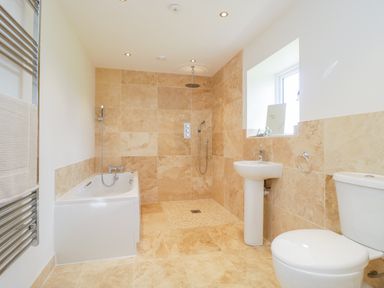 A bathroom with a bathtub shower pedestal sink toilet and towel rack at Golden Valley Barn in Oldbury-On-Severn