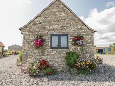 A stone building wall with a window and flower planters at Golden Valley Barn Oldbury-On-Severn