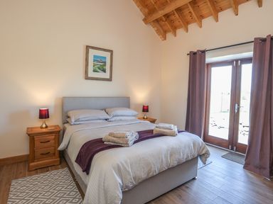 A bedroom with a double bed bedside tables lamps and curtains at Y Bwthyn in Brynsiencyn