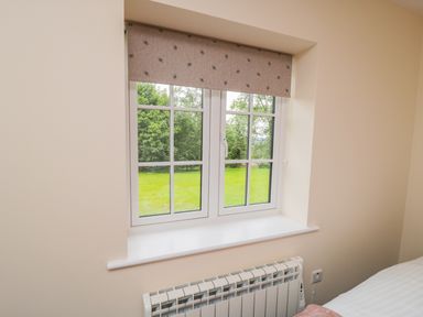 A window with a patterned blind above a radiator in a room at Ryedale Country Lodges - Hazel Lodge in Kirkbymoorside