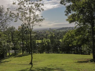 A grassy area with scattered trees overlooking fields and hills at Ryedale Country Lodges - Hazel Lodge in Kirkbymoorside