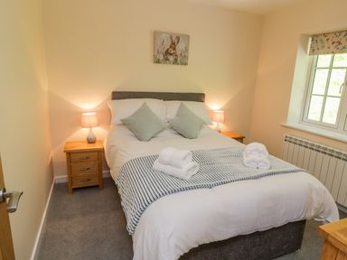 A bedroom with a double bed two bedside tables with lamps and a window at Ryedale Country Lodges - Willow Lodge in Kirkbymoorside